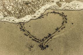 a heart in the sand with a wave