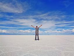 back view of man with wide open hands in Salt Desert at sky, Bolivia, Uyuni