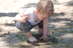 child plays in a Mud Puddle
