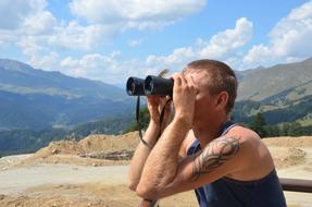 man looks through Binoculars in the Distance