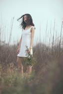 Girl in white dress with plants in her hand among the plants