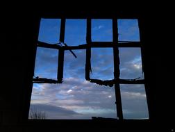 Photo of broken window at background of blue sky