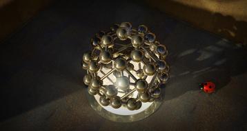 metal sculpture of an atom and a ladybug