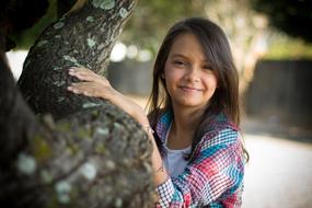 young girl behind a tree