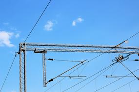 Railway cables with electricity, under the blue sky with clouds