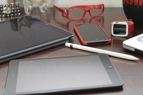 Glasses, pen, tablets, smartphone, and smartwatch on the table