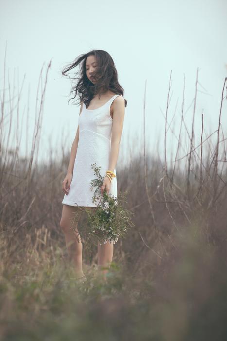 Girl in white dress with plants in her hand among the plants