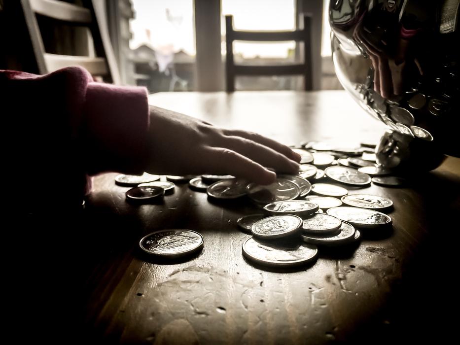 Retro photo with close-up of the person touching coins on the table in light, among the darkness