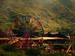 Ferris wheel in the park against a mountain backdrop