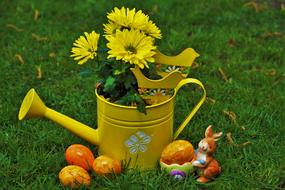 yellow watering can in the garden with orange figures