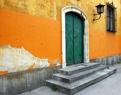 Beautiful green door of the orange building with lantern