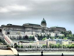 photo of a castle with a dome on the banks of the Danube river in Hungary