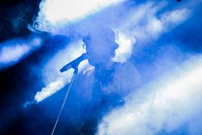 singer on stage near the microphone in a blue haze