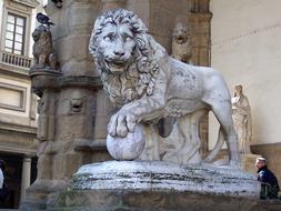 Lion with paw on ball, aged sculpture