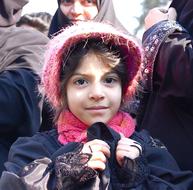 child wearing pink hat in crowd in tehran