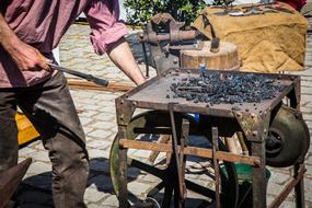 Blacksmith working with iron on the forge, outdoors