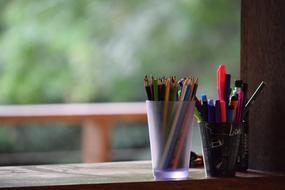 colored pencils with a pen in a glass on the window