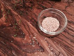 Sesame seeds in bowl on Wooden surface