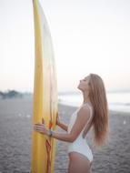 beautiful girl with yellow surfboard on the beach