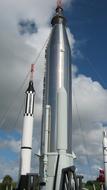 Mercury and Gemini rockets, at blue sky with white clouds on background