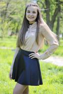 Beautiful, smiling girl student in the skirt, among the trees