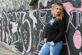 photo of a girl by the wall with black-pink graffiti