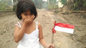 little girl with indonesian flag among nature