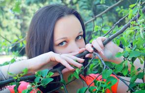 brunette hides her face behind tree branches