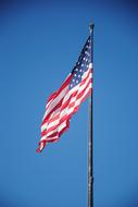 unfolding usa flag against the blue sky