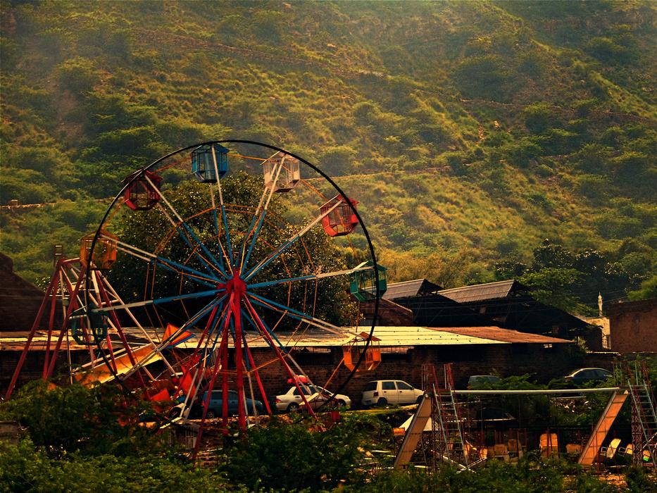 Ferris wheel in the park against a mountain backdrop