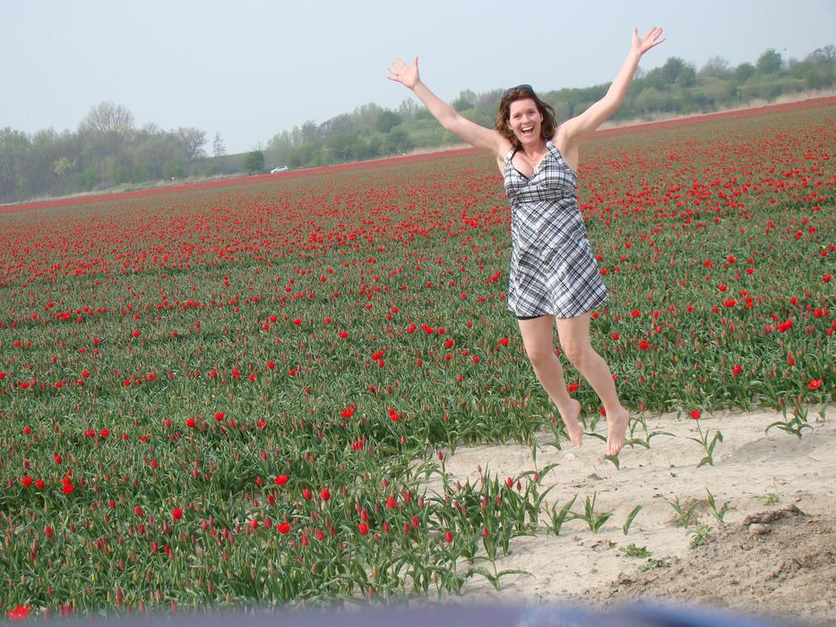girl jumping in a field of tulips
