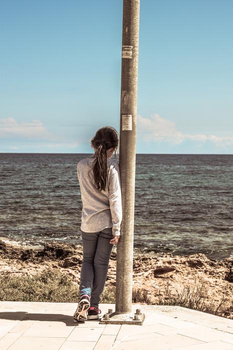 child Girl leaning on pillar in front of sea