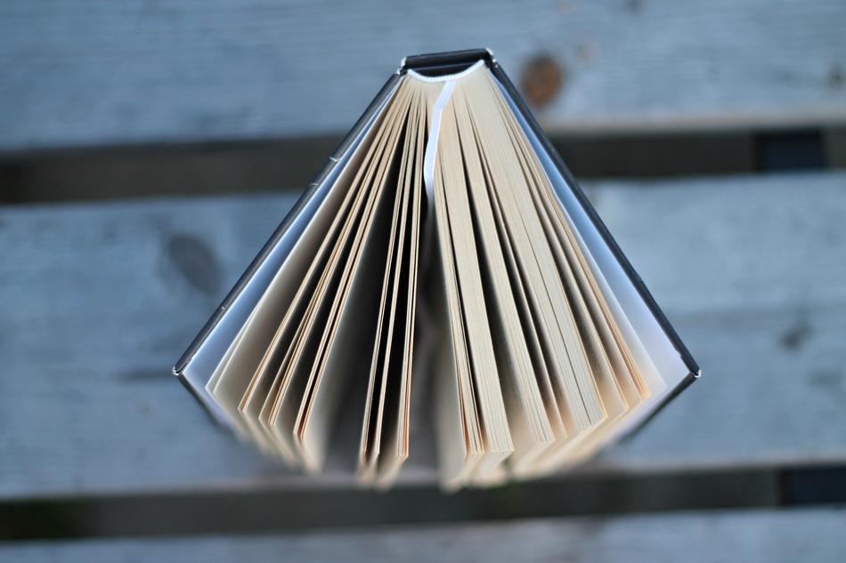 Top view of the open book with the pages, on the wooden surface