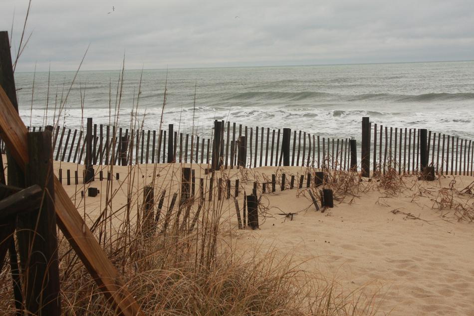 wooden fence on the beach with the sea
