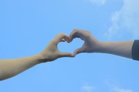 hands joined in hearts against the sky