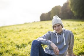 photo of a young man in a knitted hat on a green meadow