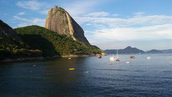 floating ships in the sea against a backdrop of rocks