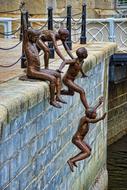 bronze sculptures of people jumping the fence