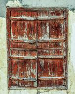 Old red and brown wooden window shutters in the wall in Paralimni, Cyprus