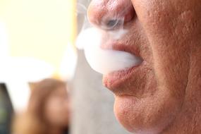 man lets the smoke out of his mouth