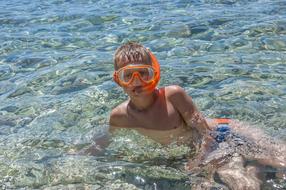 portrait of Child Boy in mask sits in water