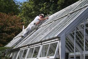 man is repairing the roof of a greenhouse