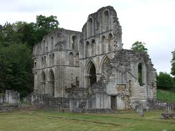 Beautiful old stone abbey on the green grass near the green trees