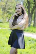 photo of a girl in a black skirt and a beige blouse in a green park