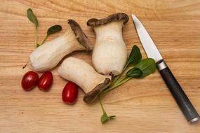 raw mushrooms on a wooden board with a knife