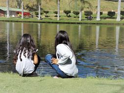 two girls sitting by a lake