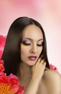 brunette among flowers on a pink background