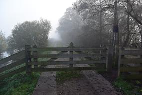wooden gate with a fence against a background of fog