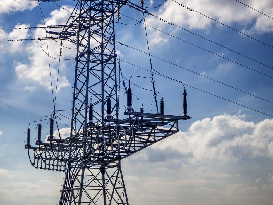 metal power line with the wires, under the blue sky with clouds