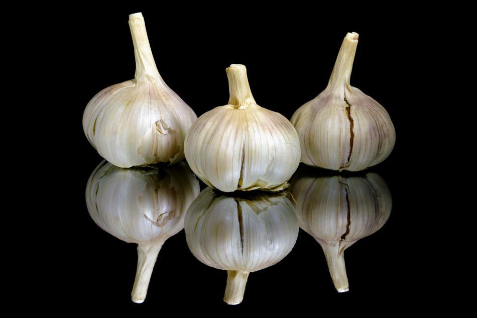 three white garlic on a black background